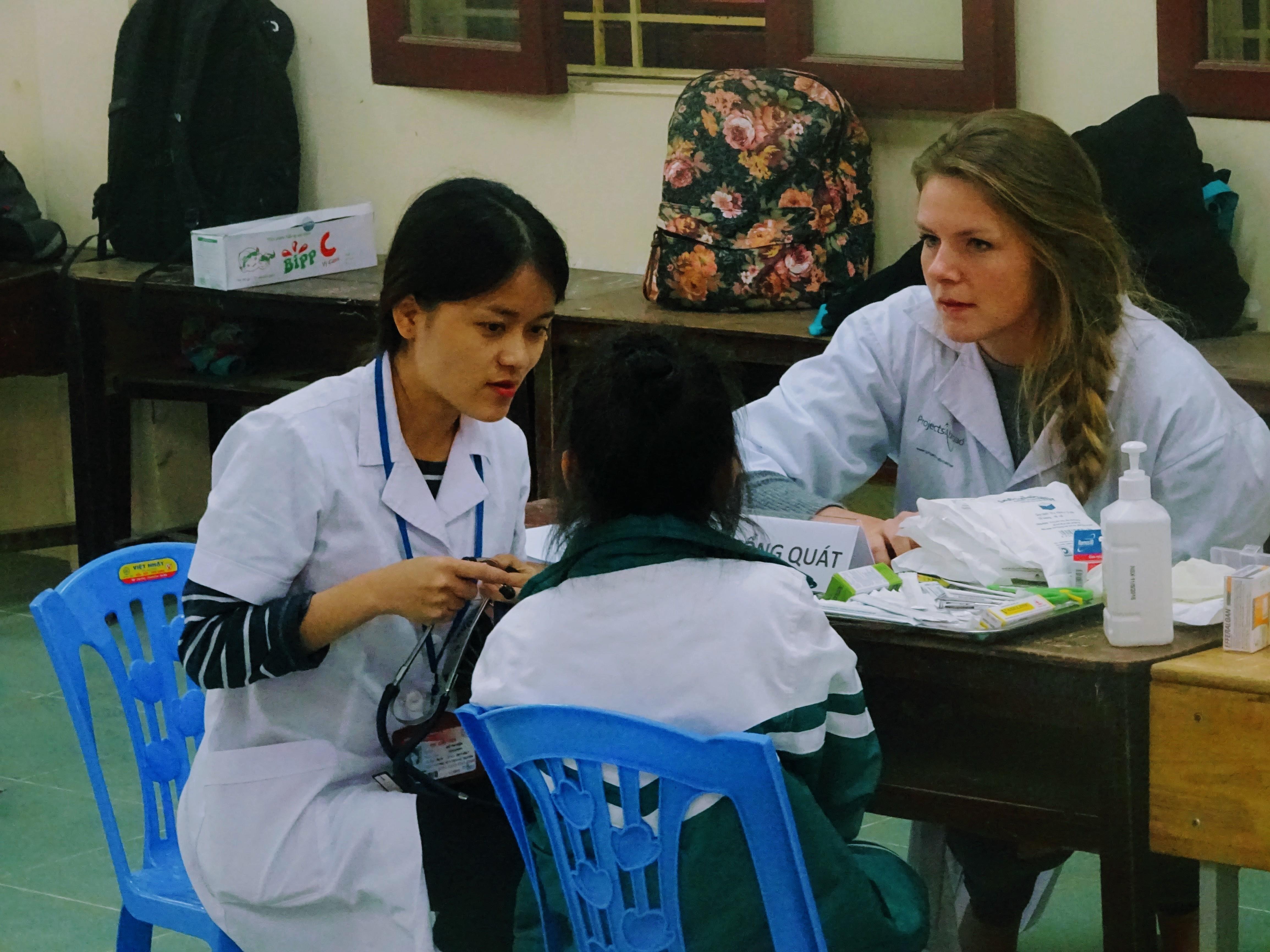 A student assists a local dentist during an outreach on the Projects Abroad Dentistry Internship in Vietnam. An intern gains dental work experience in Vietnam by helping a local dentist as she works with a patient at an outreach.